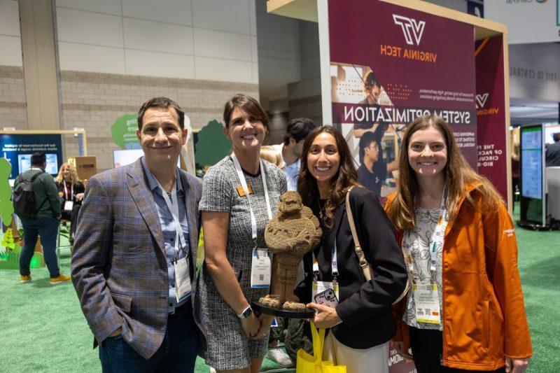 A group photo at Pack Expo in Chicago on the showroom floor with a corrugated Hokie Bird.